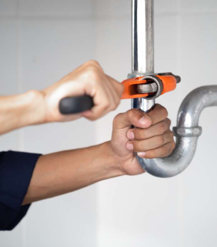 A close up shot of a plumber using a tool to repair a plumbing unit